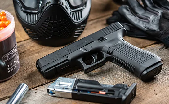 aria-label="Glock 17 Gen5 T4E Law Enforcement Training Recreational Training Glock Paintball Maker on table with paintball mask ammo CO2 and extra GLOCK paintball magazine"